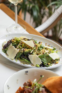 Parmesan yapraklı taze yeşil salata fındık ve şarap ile servis edilen şifalı otlar.