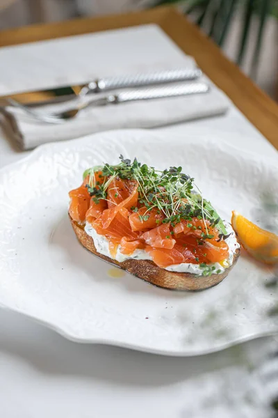 Taze somon dilimleri, mikroçerezler ve beyaz tabakta servis edilen baharatlarla kaplı avokado tostu.