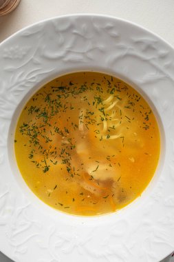 Zarif beyaz kasede servis edilen sebzeli ve şifalı tavuk çorbası.