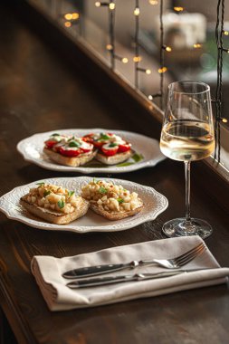 Taze domatesli iki bruschetta porsiyonu ve restoranda beyaz tabakta servis edilen tatlı armut.