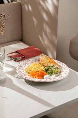 Çırpılmış yumurtalı kahvaltı tabağı füme somon brokoli ekşi krema ve çiçek tabağında kızarmış ekmek.