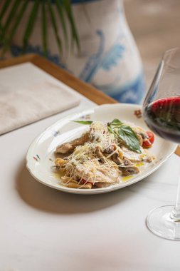 İtalyan tavuklu makarna ve mantarlı rendelenmiş peynir ve restoran masasında kırmızı şarap.