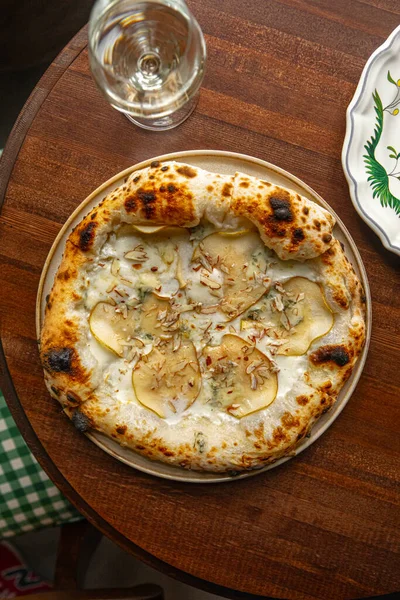 İtalyan usulü pizza dilimlenmiş armut gorgonzola peyniri ve ahşap masada servis edilen kremalı beyaz sos.