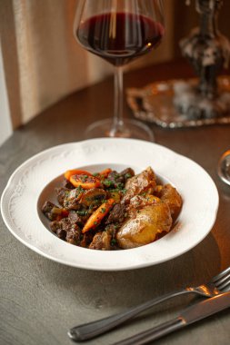 Klasik Fransız bifteği burginyon patates ve havuçla servis edilen kırmızı şarapla şık mum ışığında servis edilen