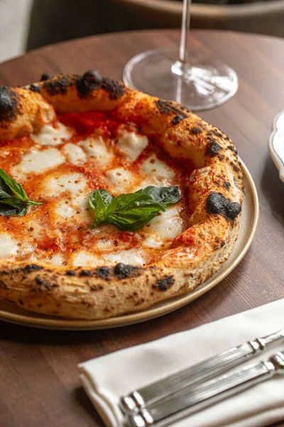 Eritilmiş mozzarella soslu klasik pizza margherita ve kırmızı şarapla servis edilen taze fesleğen.