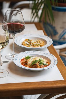 Geleneksel İtalyan lazanyası, domates soslu peynir ve kırmızı şarapla servis edilen fesleğen.