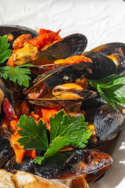 Akdeniz deniz ürünleri olarak sunulan bol otlu ve maydanozlu domates sosunda pişirilmiş taze siyah midyeler.