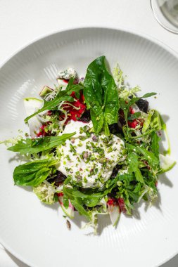 Taze restoran tarzı pancar ve kabak salatası, karışık yeşil peynir ve beyaz tabakta servis edilen otlar.
