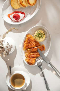Krem şantili kruvasan ve kafe ortamındaki parlak masanın üzerinde bir fincan kahve.