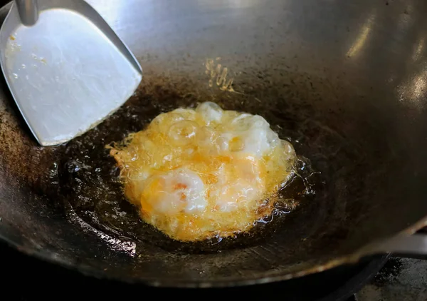 Fried eggs with vegetable oil in a pan.