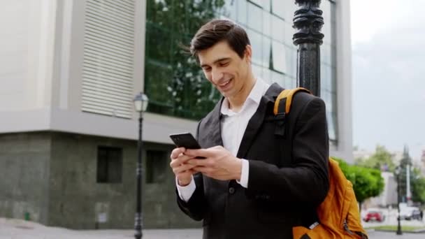 Lykkelig og smilende karismatisk ung forretningsmand midt på gaden han tager sin telefon og begynder at ringe til nogen – Stock-video