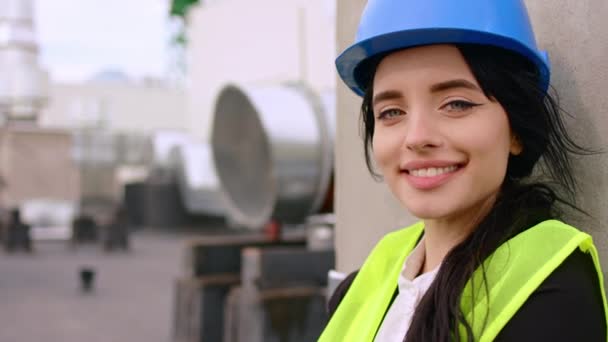 Στο εργοτάξιο στην κορυφή του κτιρίου κοιτάζοντας μπροστά από την κάμερα χαμογελώντας μεγάλο και έχουν ένα όμορφο πρόσωπο νεαρή αρχιτέκτονα γυναίκα — Αρχείο Βίντεο