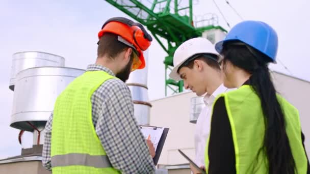 Attraente donna giovane ingegnere e uomo archiviato e uomo d'affari hanno una discussione sulla parte superiore del cantiere che utilizzano il tablet digitale per analizzare il piano dell'edificio. Girato su ARRI — Video Stock