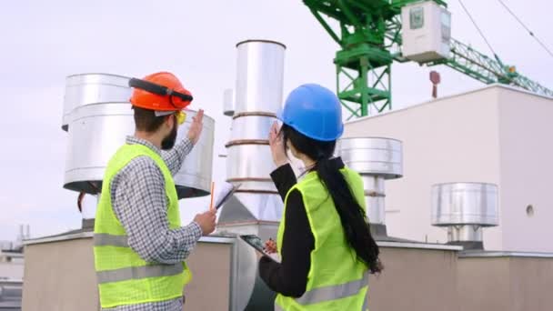 Davanti al gruppo fotografico di ingegneri e assistente hanno una discussione in cima al cantiere analizzano qualcosa utilizzando tablet digitale — Video Stock