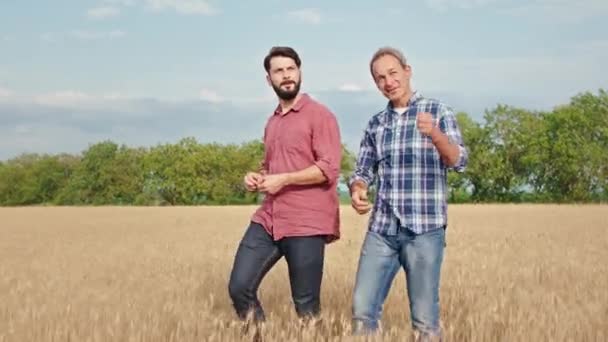 Mitt i vetefält gammal man bonde med sin son promenader jordbruk koncept i solig dag — Stockvideo