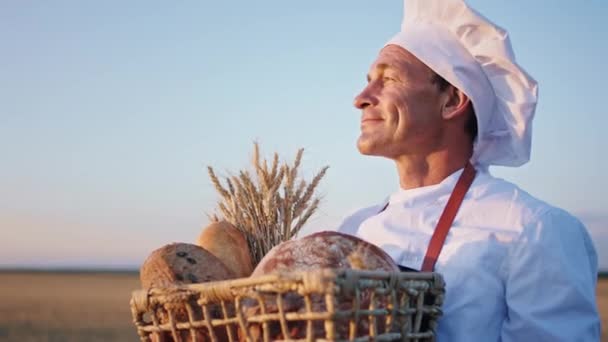 Vid solnedgången på vetefältet känner den gamle bagaren en korg med färskt bröd som doftar av kärlek till brödet och njuter av stunden — Stockvideo