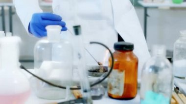 Bilim adamlarının laboratuarında kameranın önünde yakın çekim yaparken kadın bazı kimyasal maddeler ve ateş kullanarak bir deney yapıyor.