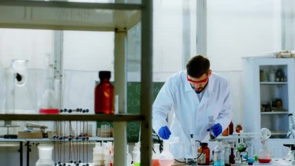 Μεγάλος φοιτητής χημείας της ιατρικής κάνει κάποιο πείραμα για την εργασία κολλεγίου του προσθέτει κάποια σκόνη στη φωτιά φοράει εξοπλισμό ασφαλείας — Αρχείο Βίντεο