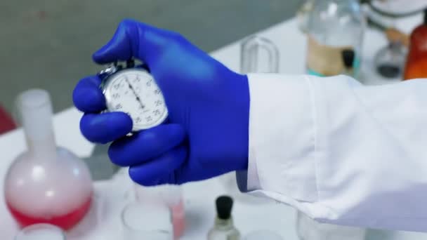 Szoros részletek egy kémiai labor tudósnál, aki a kísérletéhez kézi stopperórát használ. Lelőtték az ARRI Alexa Mini-n. — Stock videók