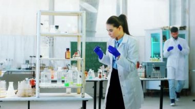 Kimya laboratuarı. İki bilim kadını ve erkek birlikte bir deney üzerinde çalışıyorlar. Bu yoğun çalışma için farklı kimyasal sıvılar kullanıyorlar.