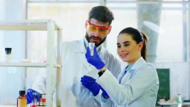 Хорошая научная команда женщина и мужчина с оборудованием безопасности, анализирующим химическую реакцию на лабораторной ванне, обсуждают счастливый и радостный результат. Снимок на ARRI Alexa Mini. — стоковое видео