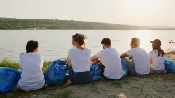 Grupul de voluntari au un timp de pauză lângă lac ei termină pentru a curăța gunoiul și să ia un loc în căutarea spre lac și să se simtă minunat — Videoclip de stoc