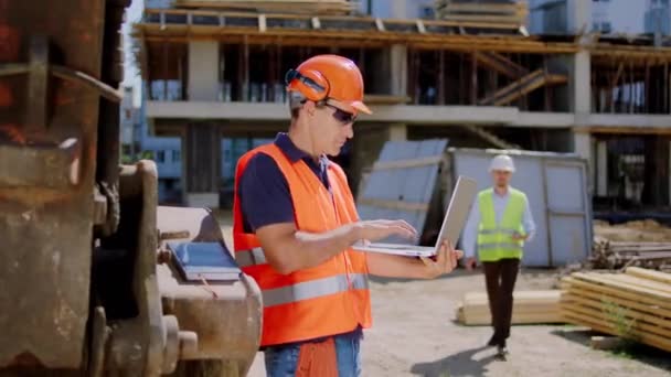 Foreman concentrated at construction site using laptop to checking the building plan the engineer guy came closer to have a discussing with the foreman. Shot on ARRI Alexa Mini — Stock Video