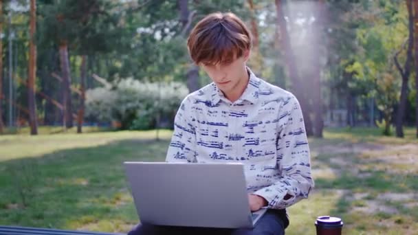 Konsep gaya hidup media sosial di taman di udara segar pemuda minum kopi di taman dan bekerja secara online menggunakan laptop — Stok Video