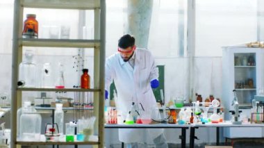 Laboratuvarda biyoteknoloji uzmanı farklı laboratuvar sıvıları kullanarak kimyasal reaksiyon deneyleri yapıyor.