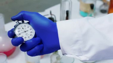 Biyoteknoloji laboratuarındaki detaylar zamanı düzeltmek için manuel kronometre kullanarak kimyasal reaksiyon testi yapıyor.