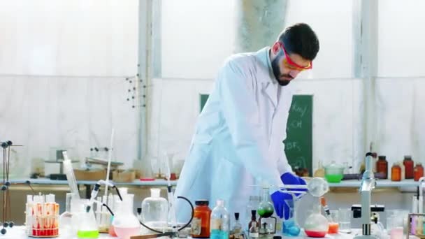 Médicaments étudiant homme dans le laboratoire de chimie en utilisant une baignoire de laboratoire liquide bleu pour la réaction de la substance d'essai — Video