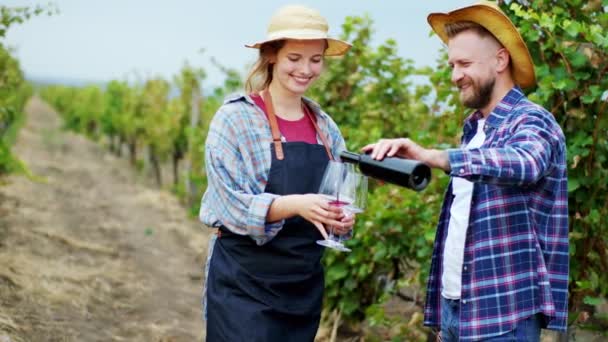 Dobře vypadající farmář rodina farmář charismatický úsměv uprostřed vinice muž vzít láhev vína a nalít do sklenic, zatímco dáma drží. 4k — Stock video