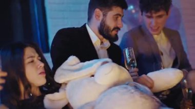 Partide birlikte gülümseyen güzel bir grup öğrenci mutlu ve rahat bir atmosferde biraz köpüklü şarap içiyorlar. ARRI Alexa Mini 'de çekilen