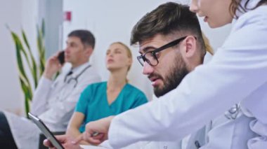 Günümüz hastanesinde genç doktorlar kadın ve erkek dijital tableti alarak diğer hemşirelerin ve doktorun telefonda konuştuğu başhekimin sosyalleşmesini analiz ederler.