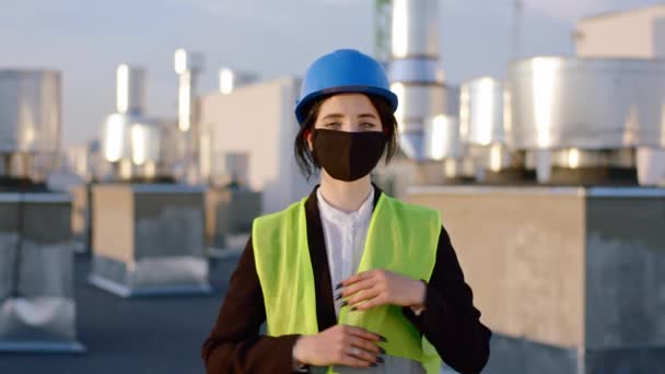 Delante de la cámara hermosa dama tomar de la máscara protectora en la pandemia que trabaja en la parte superior del sitio de construcción ella sonriendo lindo — Vídeo de stock