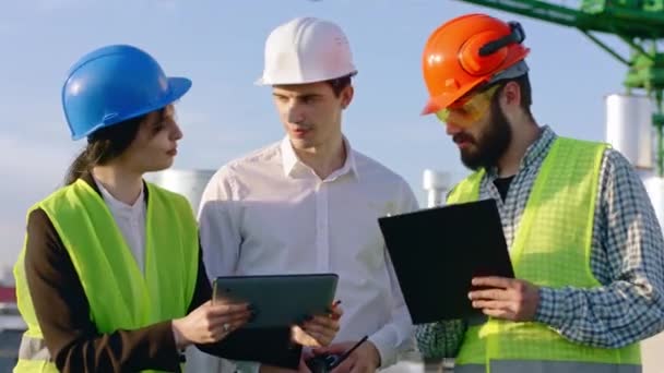 Proche de l'homme d'affaires de la caméra et deux ingénieurs analysant le plan futur du chantier ils utilisent une tablette numérique — Video