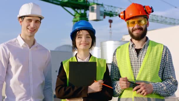 Portrait of a group of specialists in a construction site looking straight to the camera and smiling large they looking straight to the camera — Stock Video