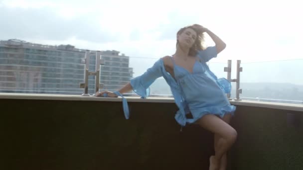 Piękna kobieta z blond włosami na dachu mieszkania na poddaszu w piżamie pozowanie romantyczne przed kamerą — Wideo stockowe