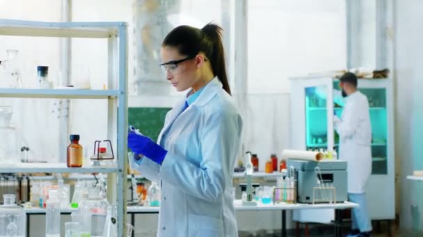 Kémia laboratóriumi tudós nő a kémiai laboratóriumban dolgozik koncentrált ő vesz néhány üveg cső kémiai oldatok — Stock videók