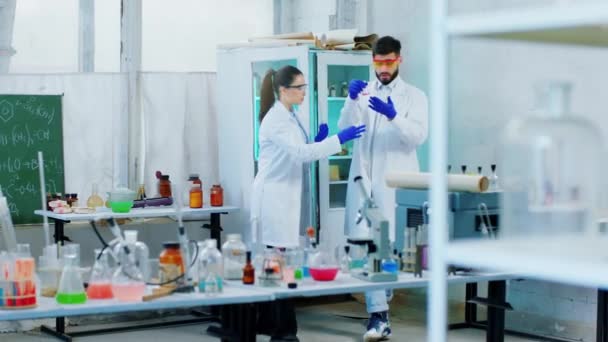 Estudiantes de medicina dama y hombre en el laboratorio de química haciendo el proyecto de la universidad que utilizan líquido químico en el tubo de vidrio — Vídeos de Stock