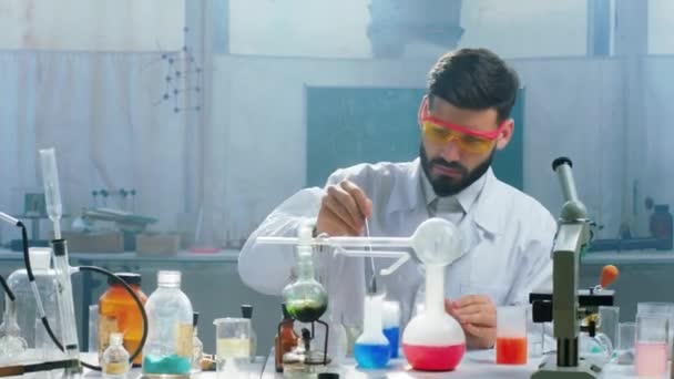 反応研究の概念と製薬業界を作るためにいくつかの粉末とガラス浴槽を使用してテストを行うバイオテクノロジー研究室の科学者の男 — ストック動画