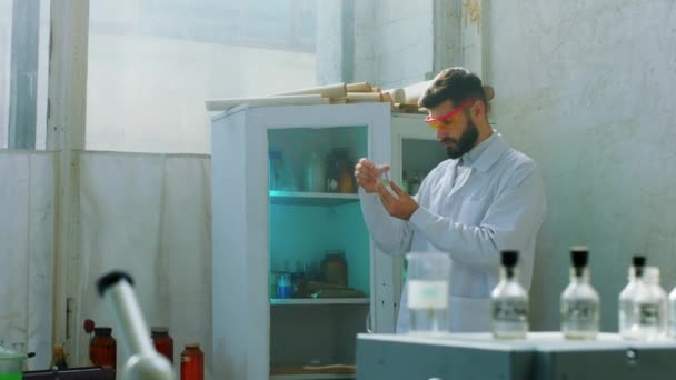 W starym laboratorium chemicznym charyzmatyczny naukowiec człowiek wziąć trochę płynu chemicznego, aby wylać na inne rurki szklane, aby zrobić badania antywirusowe koncepcji szczepionki przemysłu farmaceutycznego i — Wideo stockowe