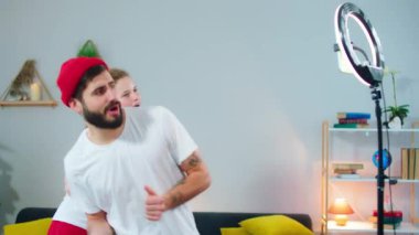 Güzel bir bayan ve erkek birlikte anın tadını çıkarıyorlar. Bir sosyal medya hesabı için hafif bir yüzük kullanarak akıllı telefonun önünde komik bir şekilde dans ediyorlar. ARRI Alexa 'da çekim