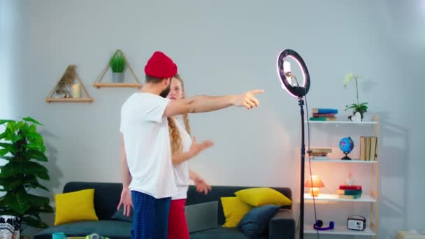 W domu w nowoczesnym salonie młoda para bardzo atrakcyjne w piżamie zrobić kilka zdjęć telefonicznych przy użyciu pierścienia świetlnego dla dobrej jakości — Wideo stockowe