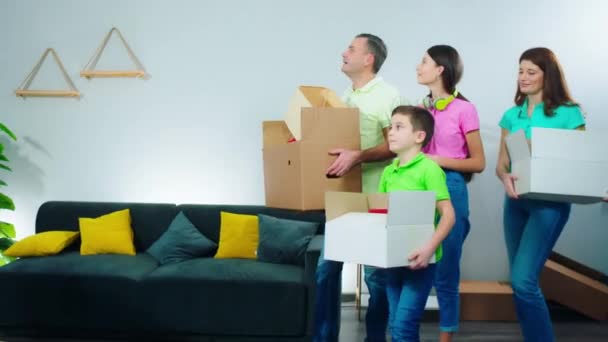 Большая семья переехала в красивый большой дом, они держат коробки с вещами, оглядываясь по сторонам возбужденными от дома — стоковое видео