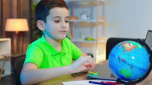Charismatický pěkný malý chlapec, zatímco dělá jeho školní projekt na notebooku vzít letadlo a hrát před kamerou — Stock video