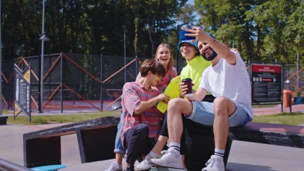 现代滑板公园的一群多种族朋友拿着一部现代智能手机自拍，他们微笑着拿着滑板 — 图库视频影像