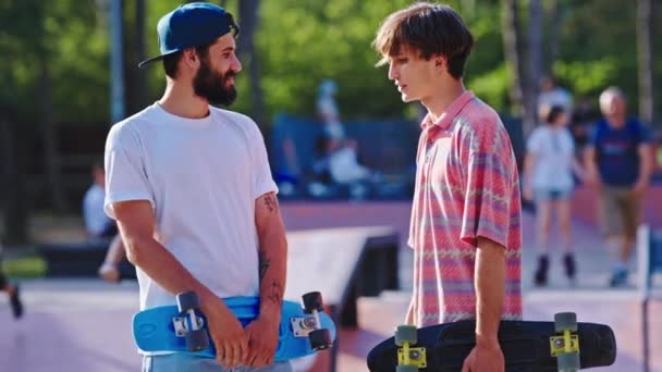 Gode venner fyre mødes i en skatepark foran kameraet de diskuterer sammen før en tur med skateboard – Stock-video