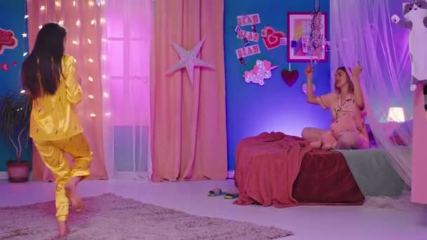 Hodná holčičí noc v ložnici dvě krásné dámy v pyžamu se baví zpíváním a tancováním — Stock video