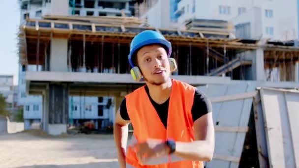 Afro travailleur américain sur le chantier de danse charismatique tout en avoir une pause écouter de la musique des écouteurs qu'il porte équipement de sécurité au travail — Video